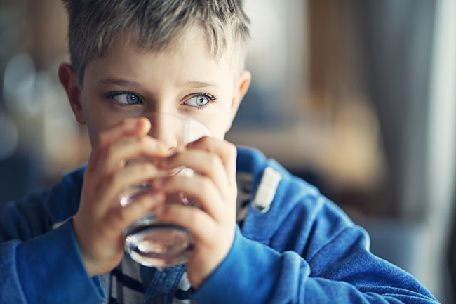 Niño pequeño bebiendo agua potable de un vaso