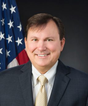 A head and shoulders photo of ATSDR Associate Director Christopher M. Reh, Ph.D. in front of a U.S. flag.