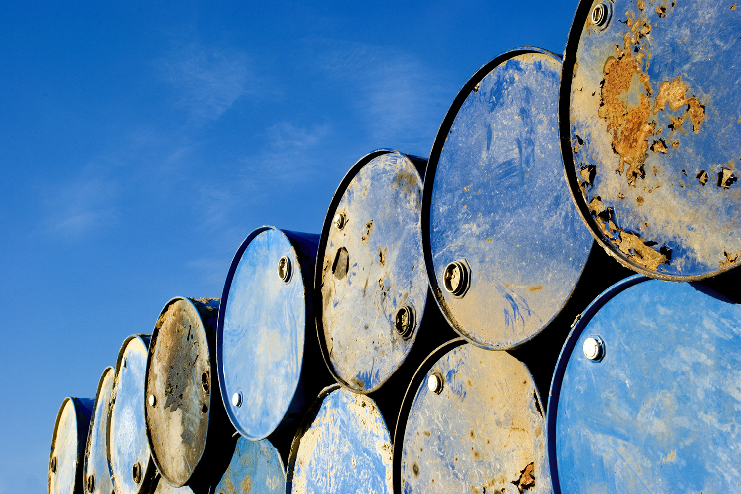 Batch of old rusty barrels against the blue sky.