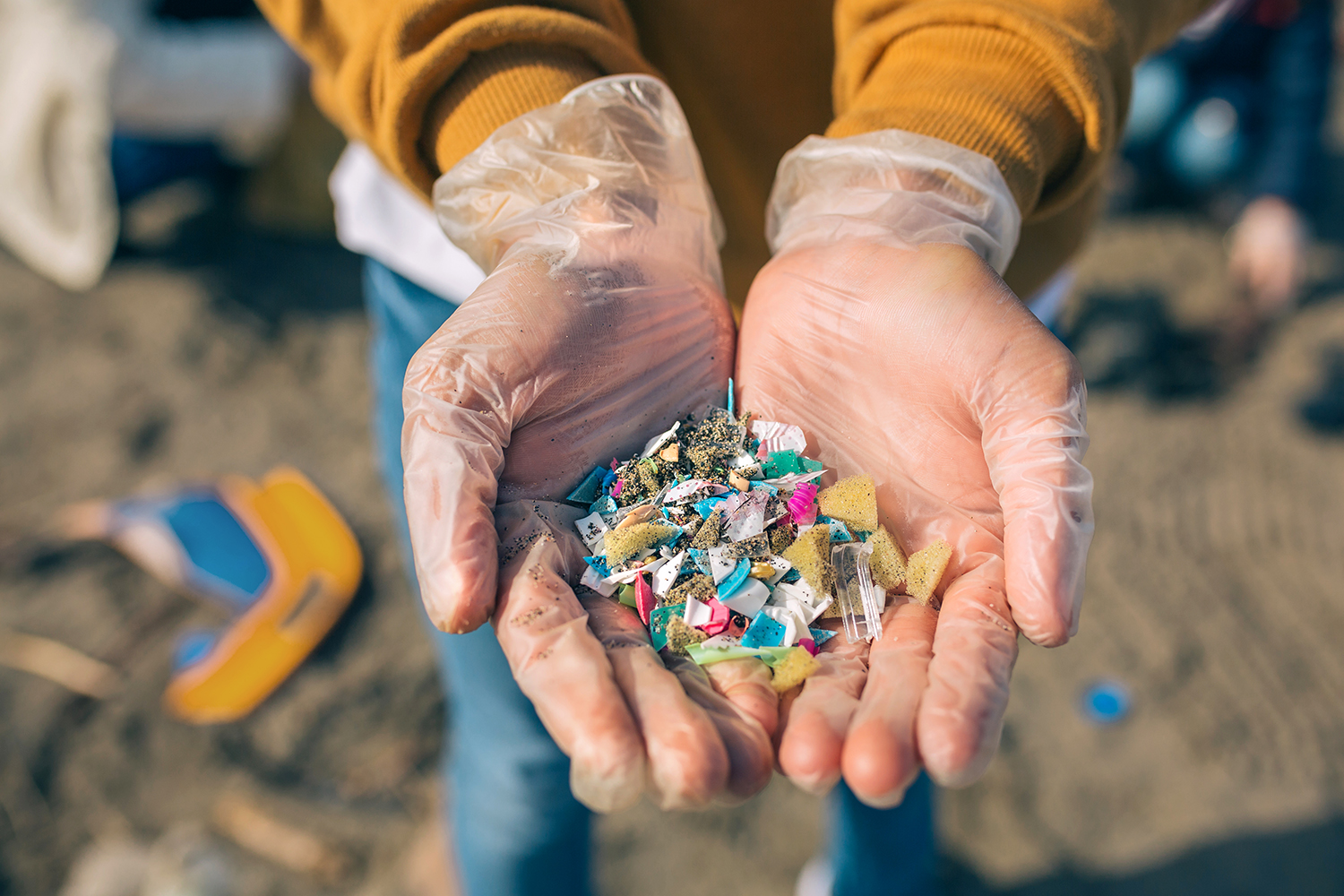 Hands with microplastics on the beach