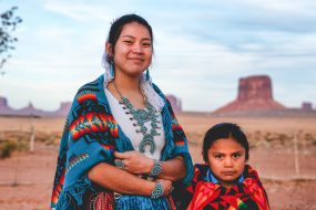 A young Navajo sister and little brother pose for photographs in their native dress