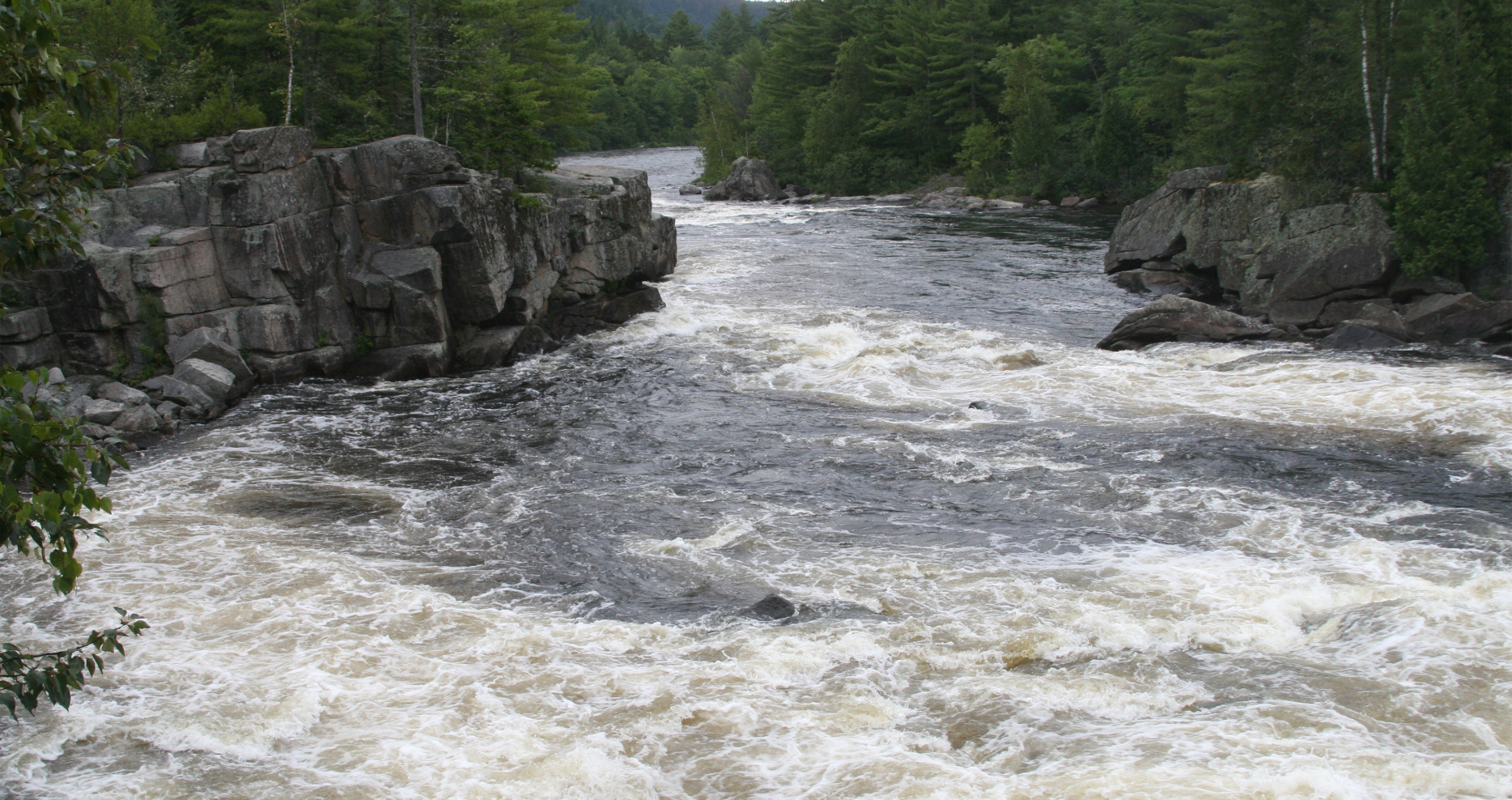 A flowing river through a valley of forest and rocks.