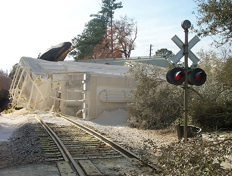 Train laying on its side off the train tracks covered in white spray.