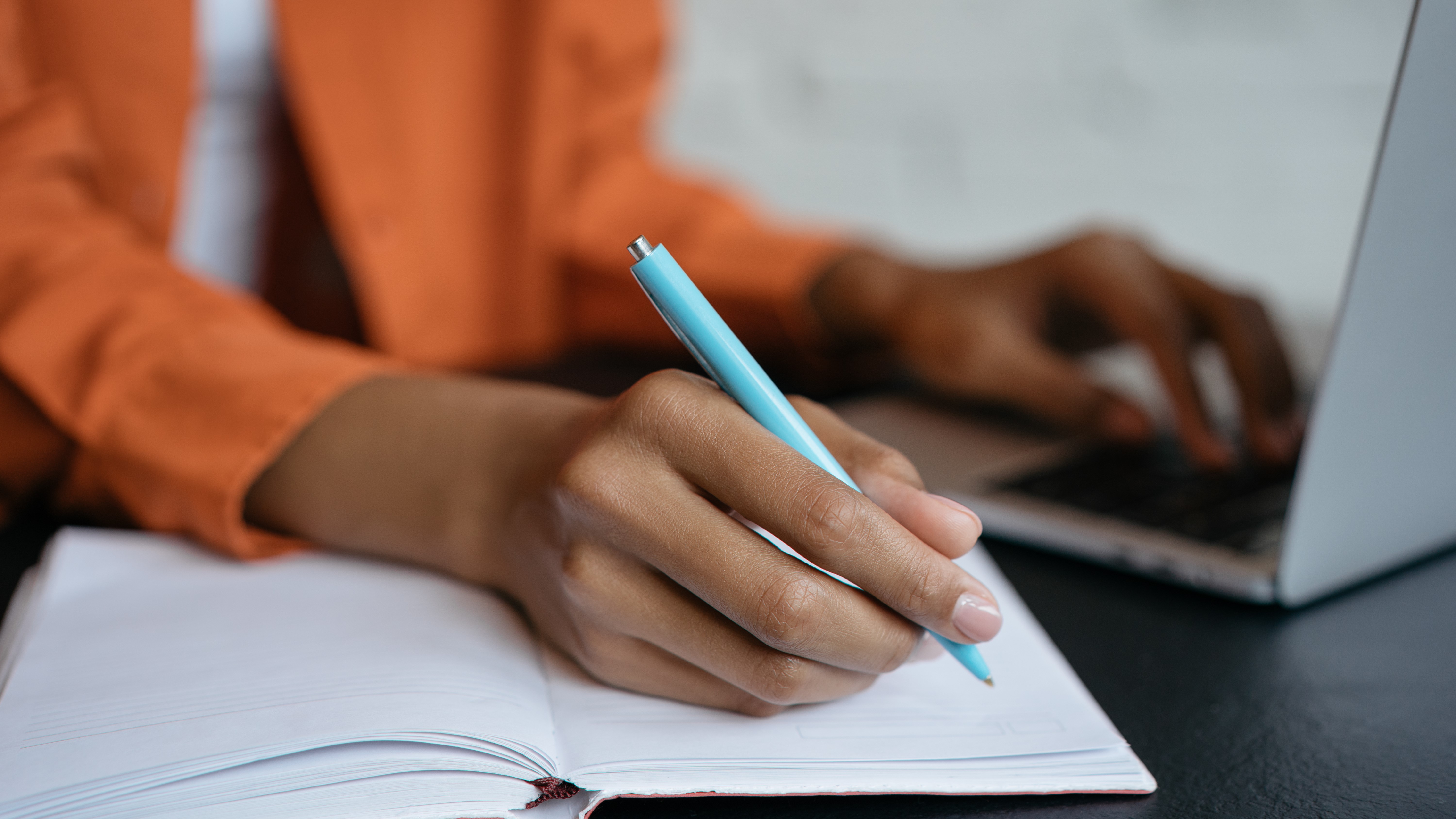 person hand holding pen and writing in notebook