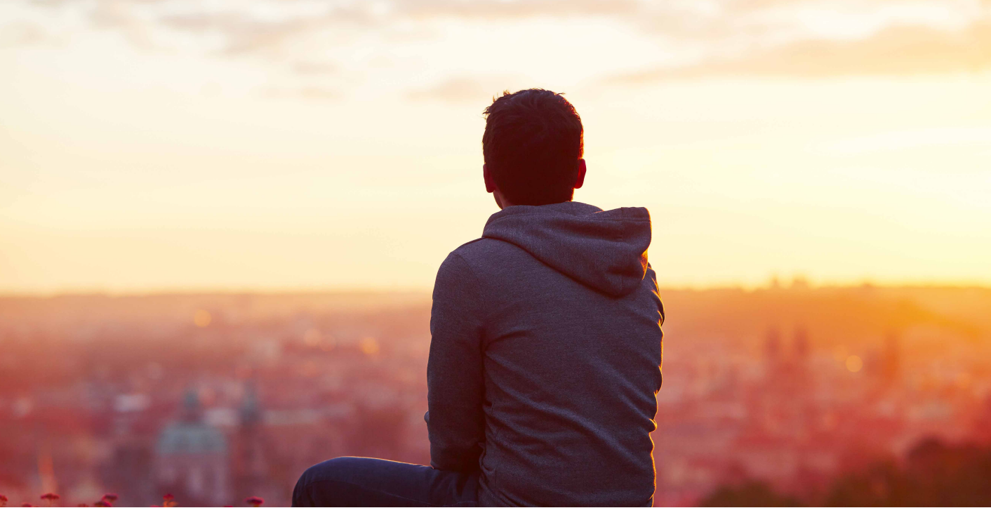 Boy sitting looking out at sunset