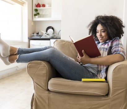Mujer sonriendo leyendo un libro en su hogar