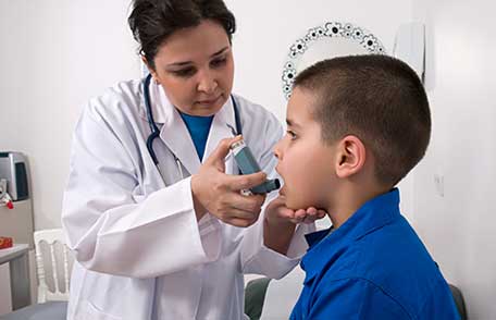 A doctor administers an asthma inhaler to a young boy.