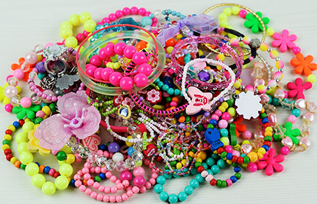 A large pile of children's toy jewelry - beads, bracelets and charms.