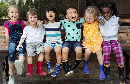 Several smiling children sitting together on a bench.