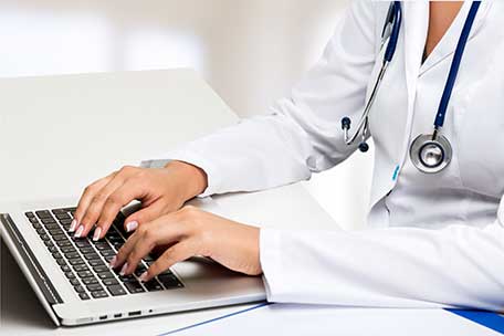 Médico utilizando el teclado de una computadora.
