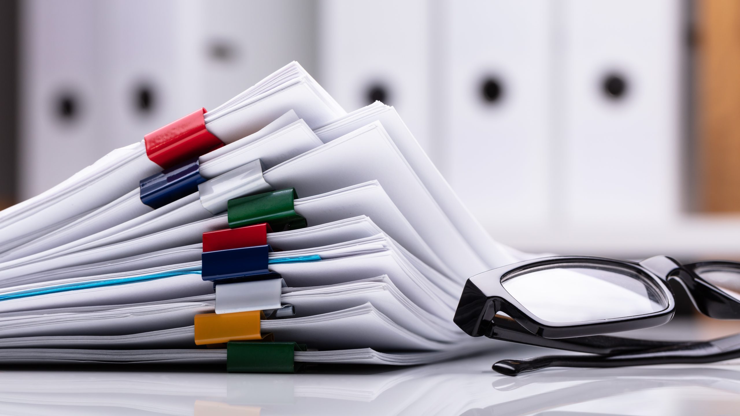 stacked documents and eyeglasses