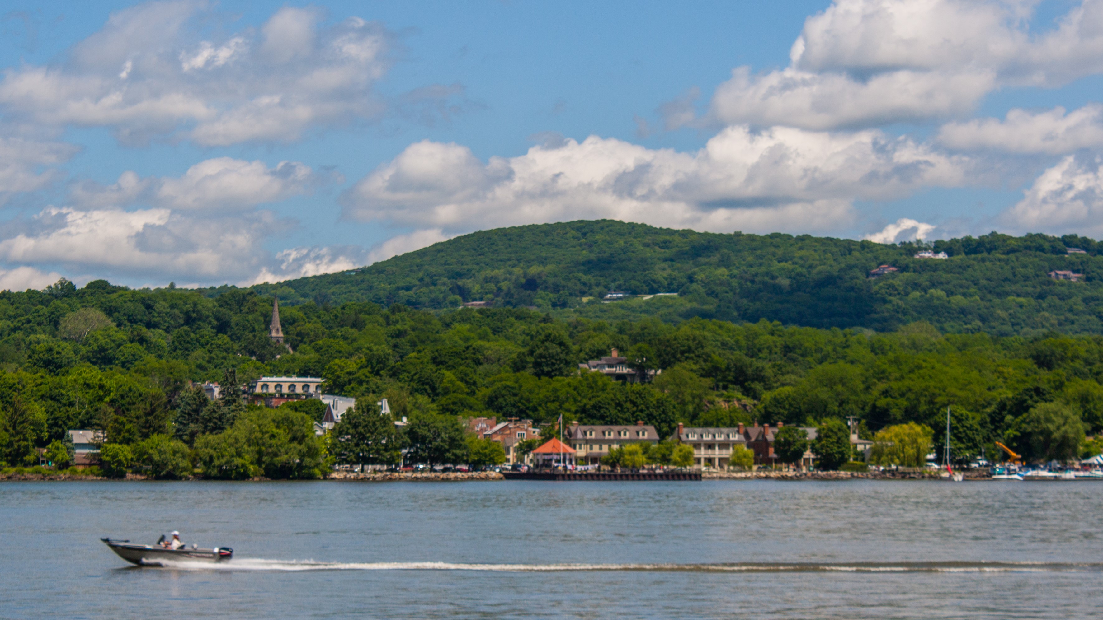 View from a river with a quaint mountainous town on the other side.