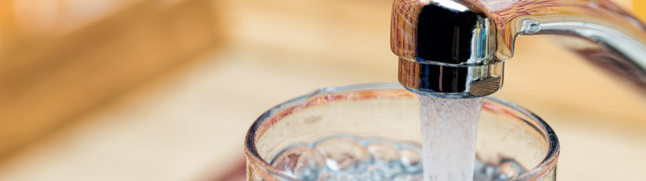 Llenar un vaso con agua potable del grifo de la cocina