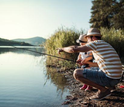 Un papá con su niño pequeño pescando en un lago