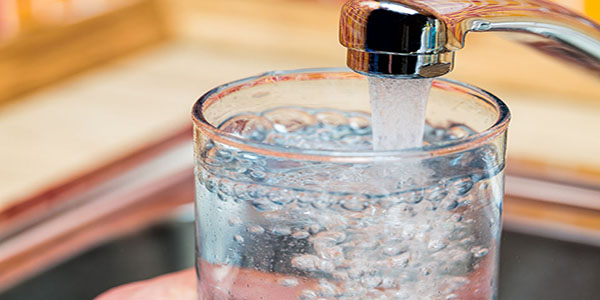 Filling up a glass with drinking water from kitchen tap.