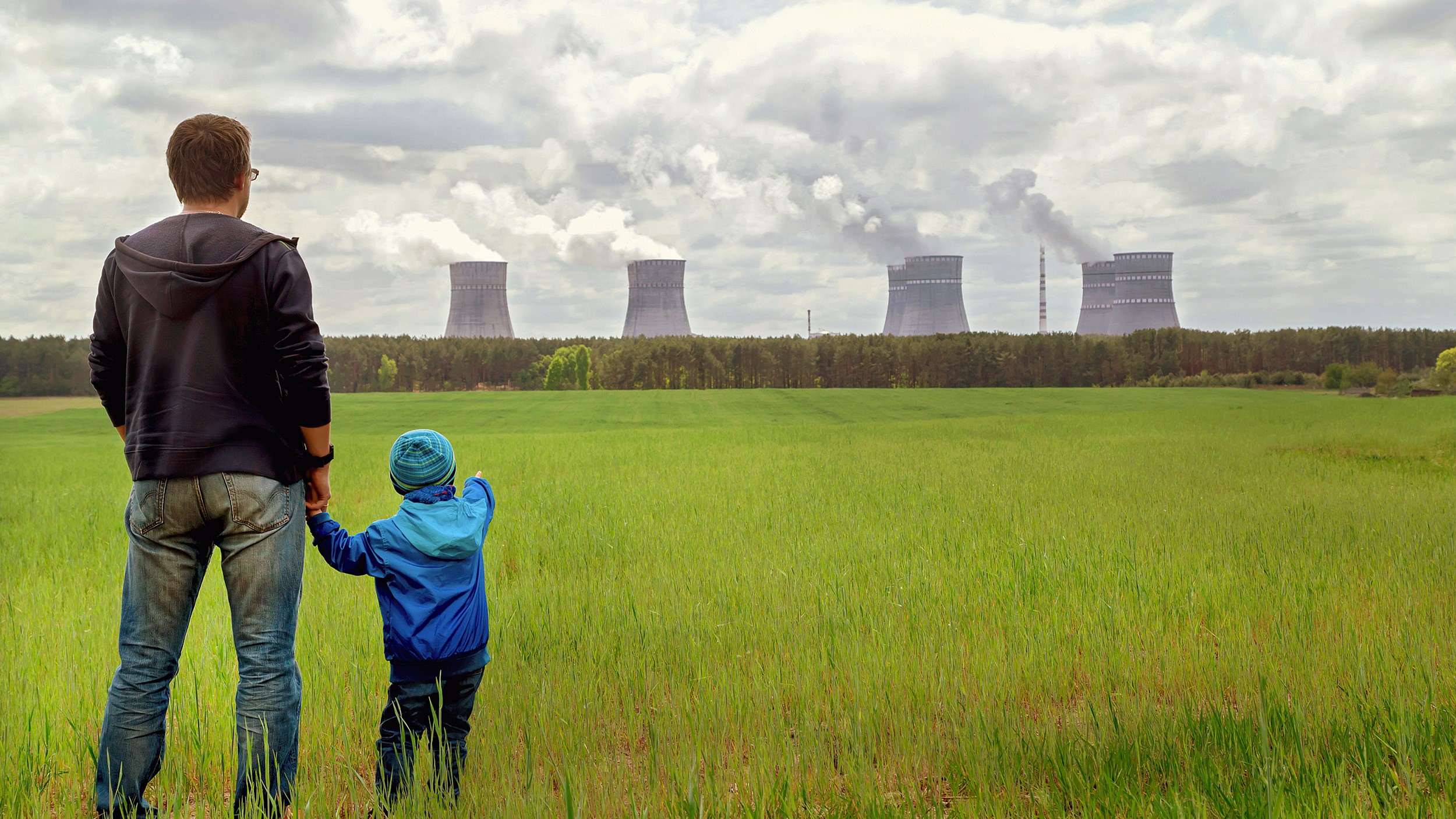A father and son looking at a power plant in the distance