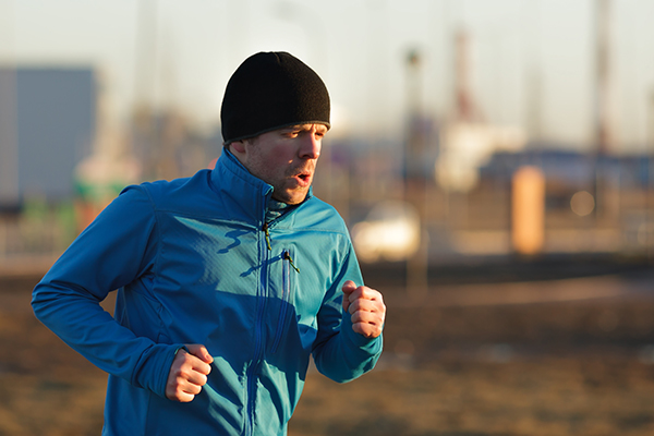 A young man in a hat and blue clothes runs in the morning