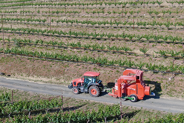 Farm tractor driving along a road while spraying pesticides & insecticides over a field