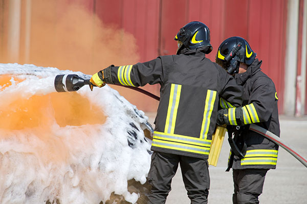 Two firefighters spraying a fire with firefighting foam