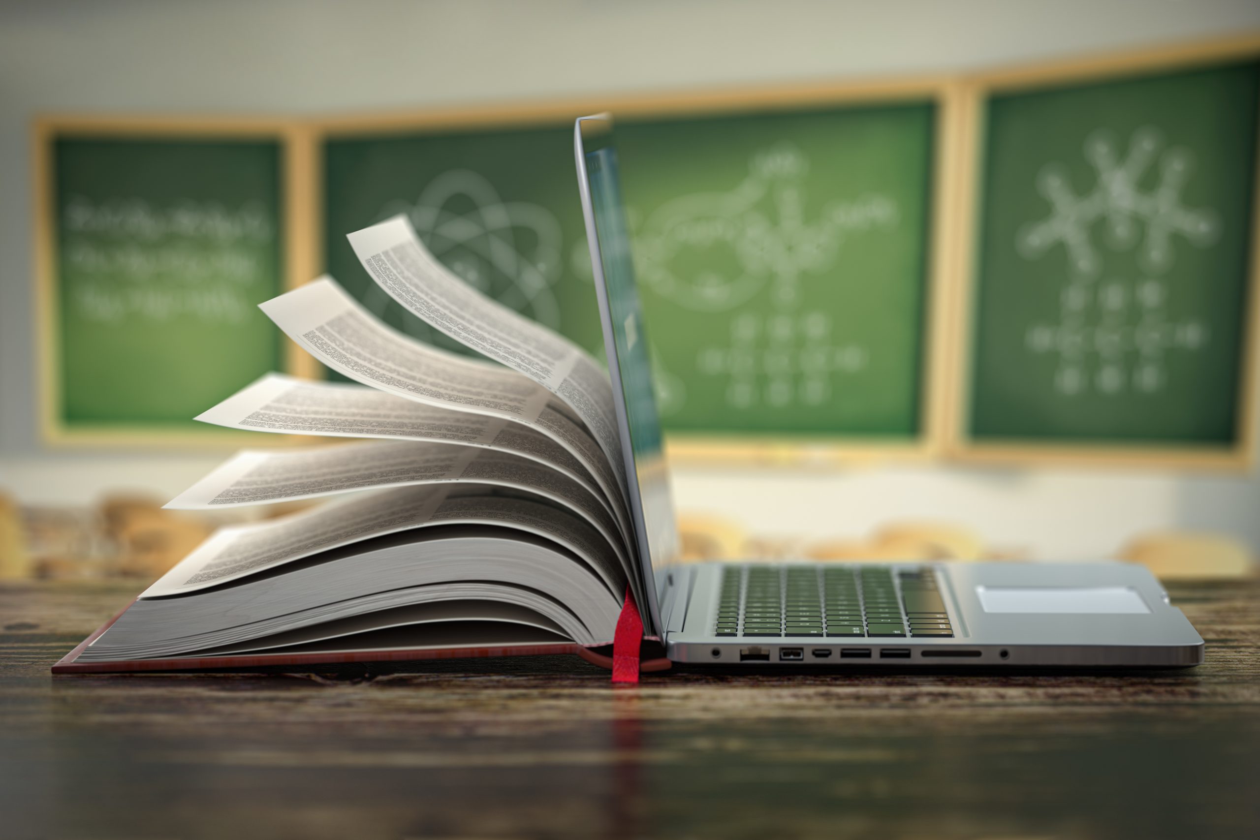 Book open on table next to a laptop