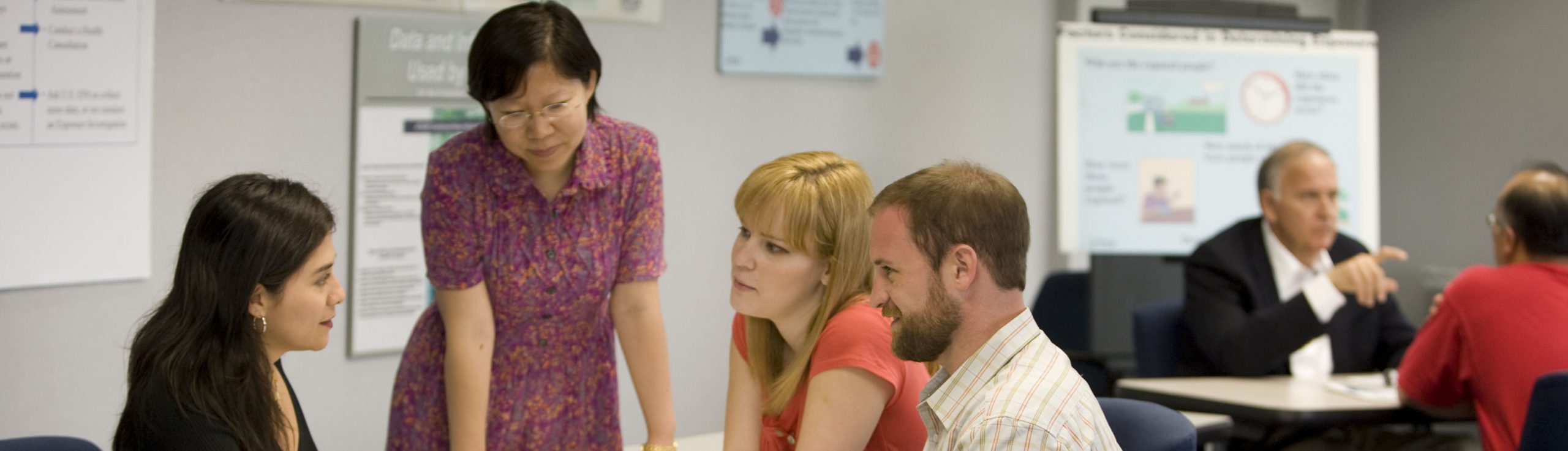 Four people gathered around a table discussing a project