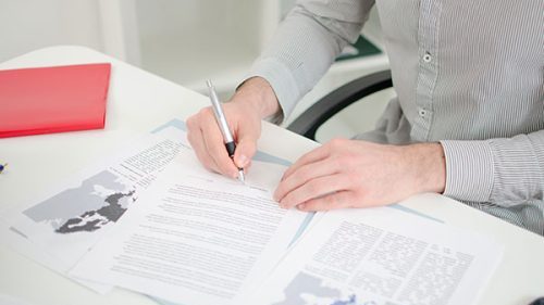 Close up of a person analyzing writing on a document.