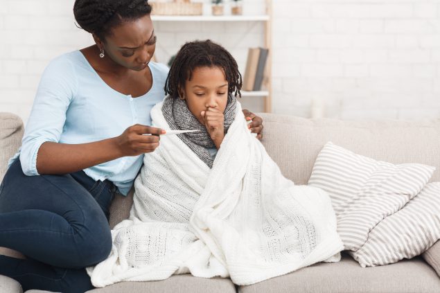 Mother measuring temperature of her sick daughter with thermometer