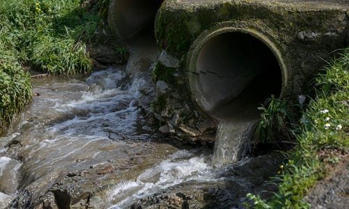 Contaminated water flowing out of a sewer pipe.